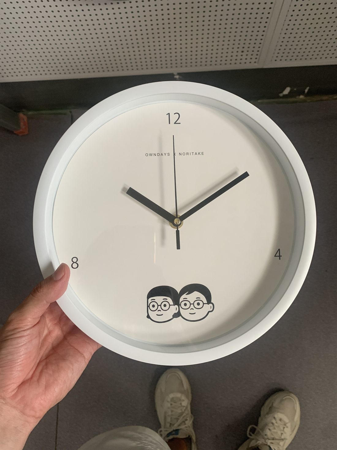 Minimal white custom wall clock with small logo and illustrated face