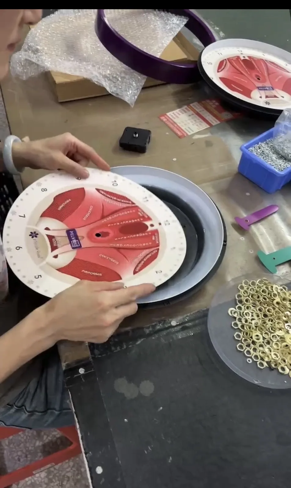 Worker assembling a printed custom wall clock with frame and clock movement parts