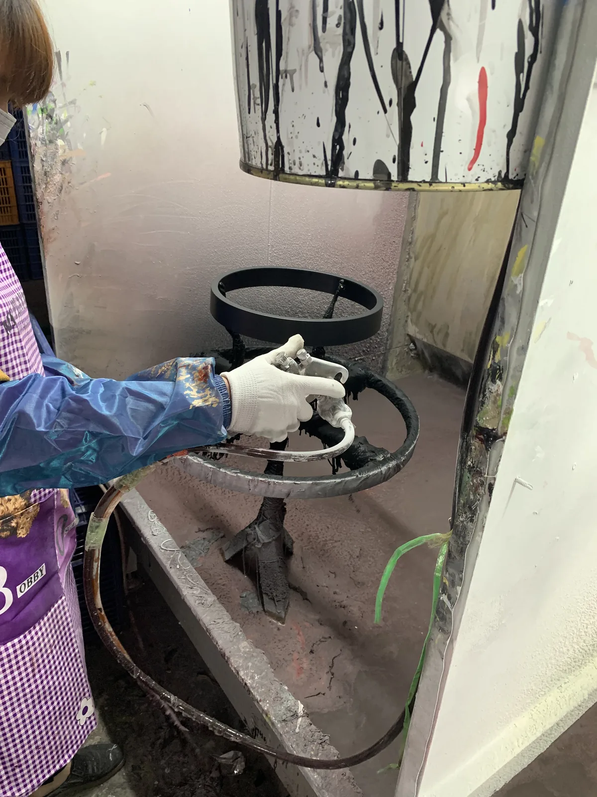 Worker spray painting a custom wall clock frame in the factory